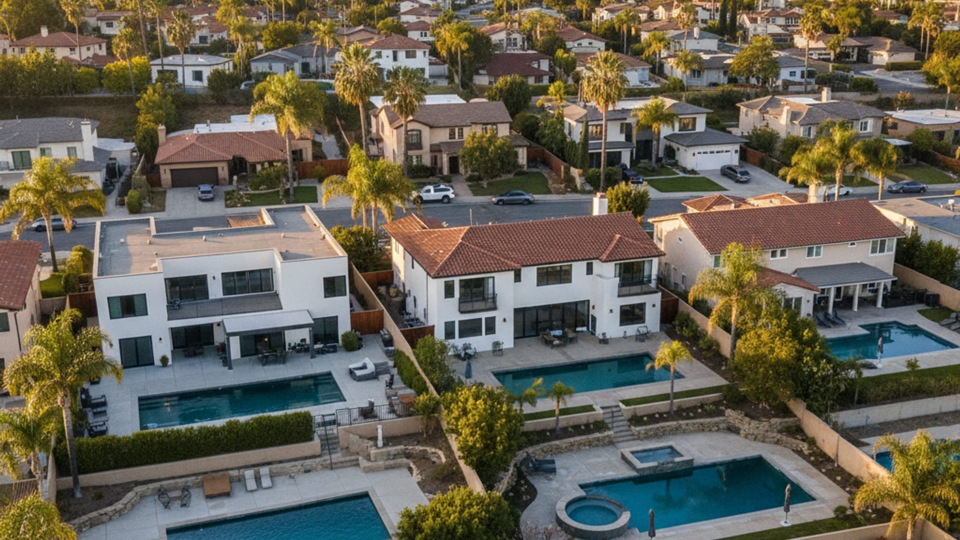 Aerial view of a San Diego County residential neighborhood with multiple pools and palm trees at golden hour